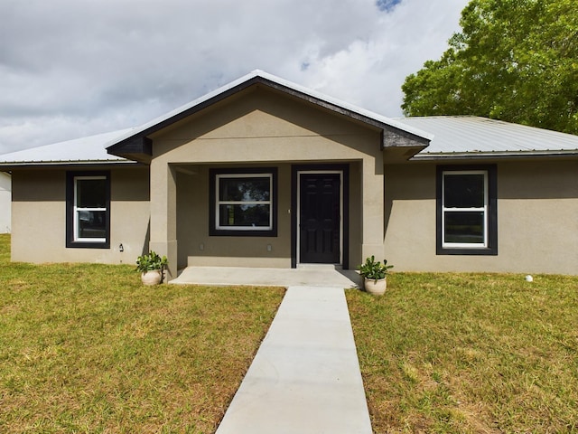 view of front of house featuring a front yard, metal roof, and stucco siding