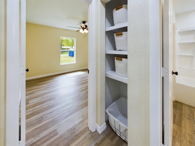 interior space with ceiling fan, baseboards, and wood finished floors