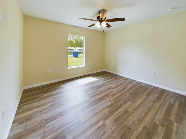 empty room with a ceiling fan, light wood-style flooring, and baseboards