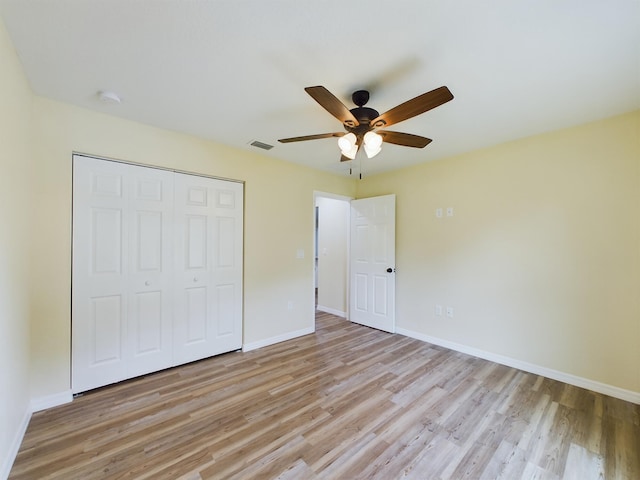 unfurnished bedroom featuring a closet, visible vents, light wood-style flooring, and baseboards