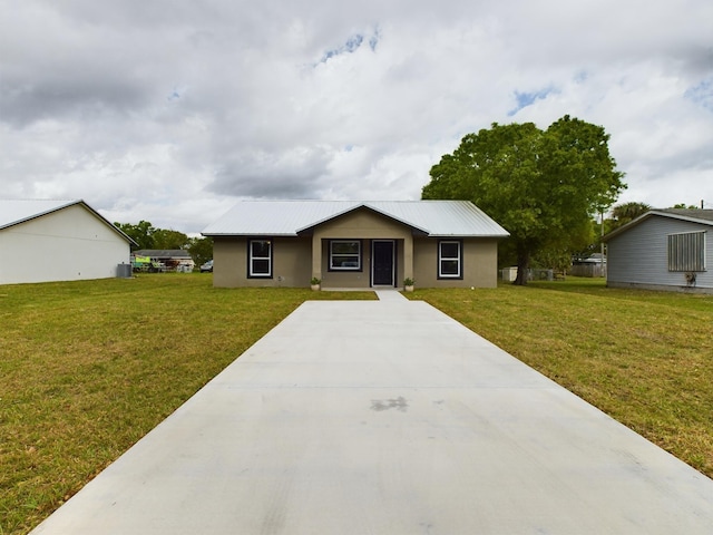 ranch-style home featuring a front yard, metal roof, and stucco siding