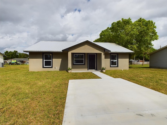 single story home featuring metal roof, a front lawn, and stucco siding