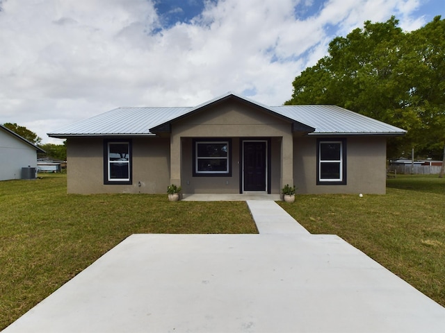 view of front of home with metal roof, a front lawn, central AC unit, and stucco siding