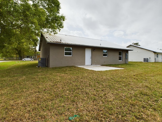 rear view of property with a patio area, a lawn, and central AC