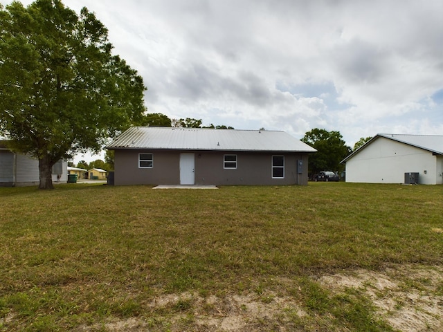 back of house featuring metal roof, central AC, and a yard