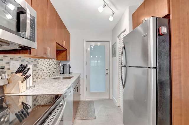 kitchen featuring decorative backsplash, brown cabinets, stainless steel appliances, light countertops, and a sink