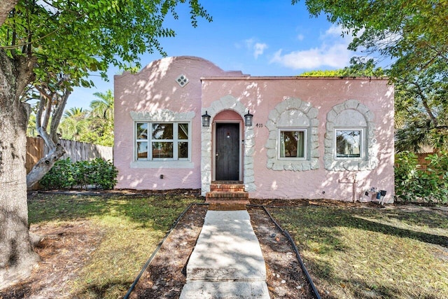 mediterranean / spanish-style home featuring a front yard, fence, and stucco siding