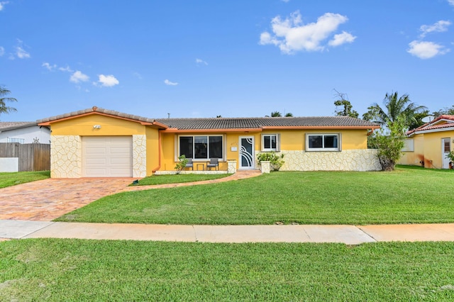 single story home featuring an attached garage, fence, decorative driveway, stucco siding, and a front yard