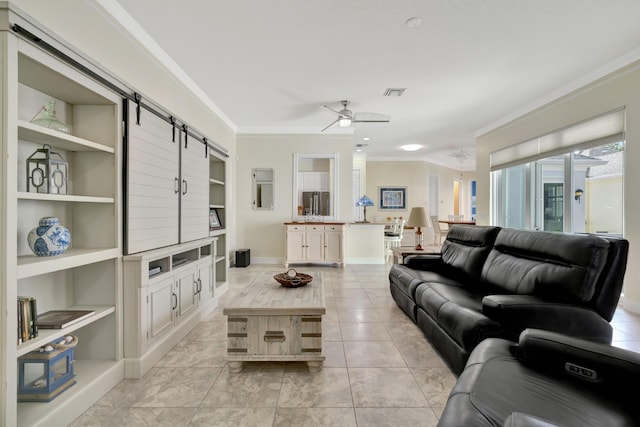 living room featuring built in shelves, ceiling fan, light tile patterned flooring, a barn door, and ornamental molding