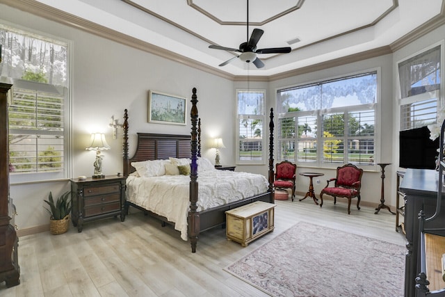 bedroom with ornamental molding, a raised ceiling, and light wood-style flooring