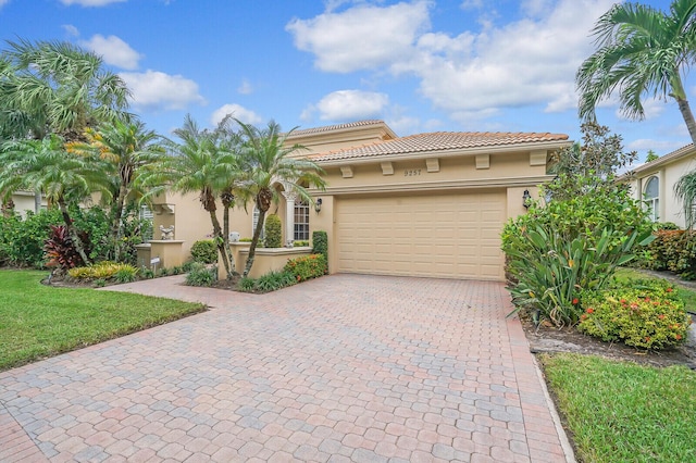 mediterranean / spanish house featuring a garage, decorative driveway, a tiled roof, and stucco siding