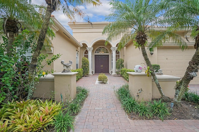 entrance to property featuring an attached garage and stucco siding