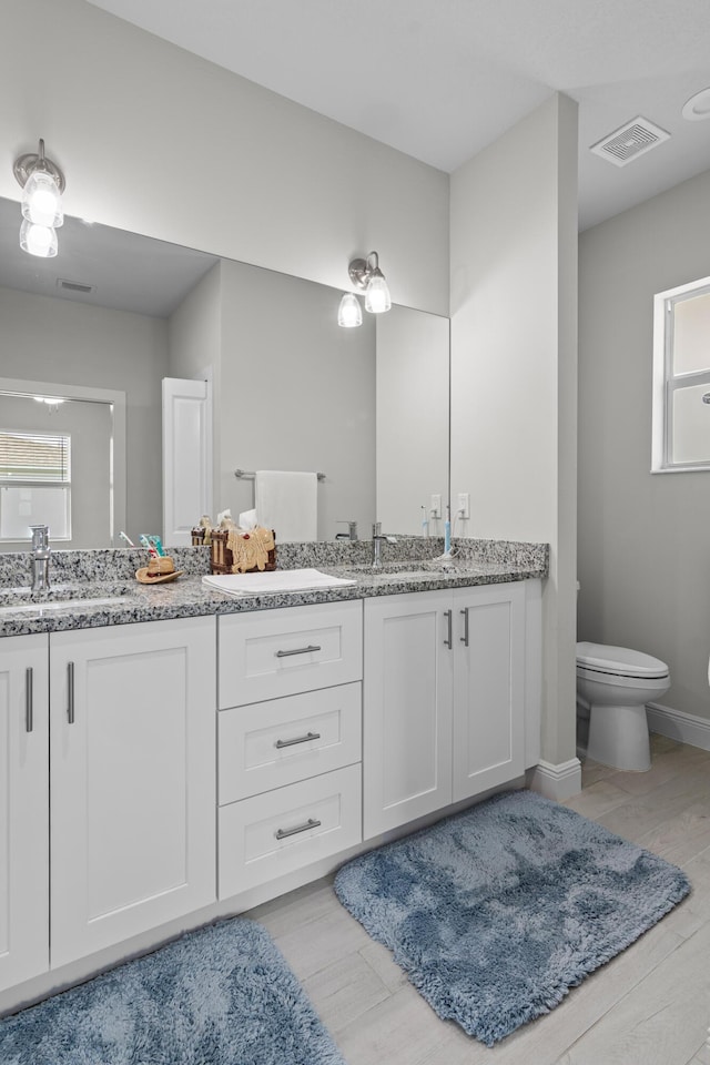 1825 SW Effland Ave, Port Saint Lucie, FL 34953 - full bath featuring double vanity, toilet, healthy amount of natural light, and wood finished floors