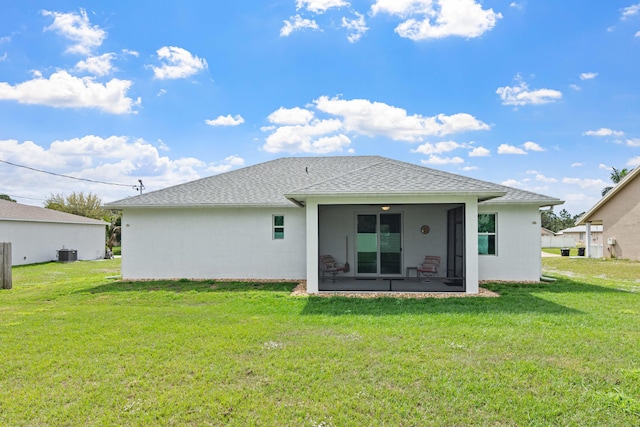 rear view of house featuring a yard, central air condition unit, and a sunroom