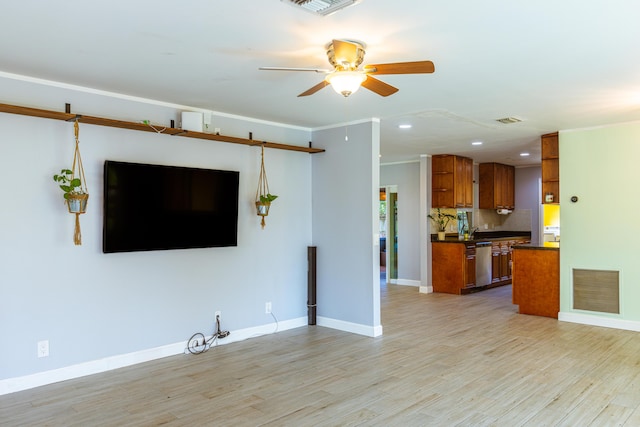 unfurnished living room featuring light wood-type flooring, ornamental molding, and ceiling fan