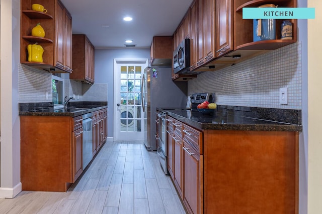 kitchen with light wood-style flooring, appliances with stainless steel finishes, dark stone countertops, open shelves, and a sink