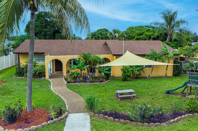 single story home featuring stucco siding, fence, and a front yard