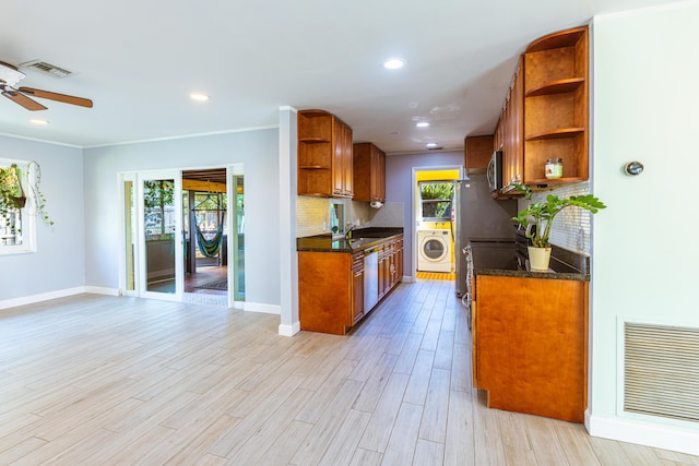 kitchen featuring light hardwood / wood-style floors, ceiling fan, stainless steel appliances, washer / dryer, and decorative backsplash