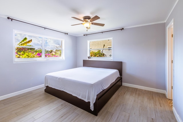 bedroom featuring crown molding, light wood finished floors, and baseboards