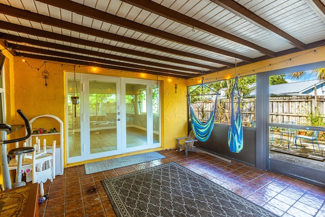 doorway to outside with beam ceiling and dark tile patterned floors