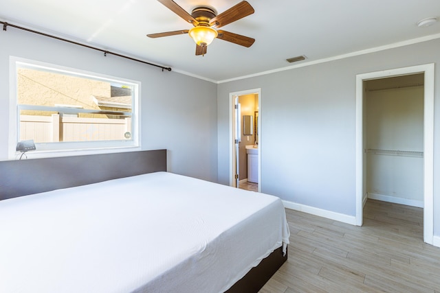 bedroom with ceiling fan, ornamental molding, connected bathroom, and light hardwood / wood-style floors