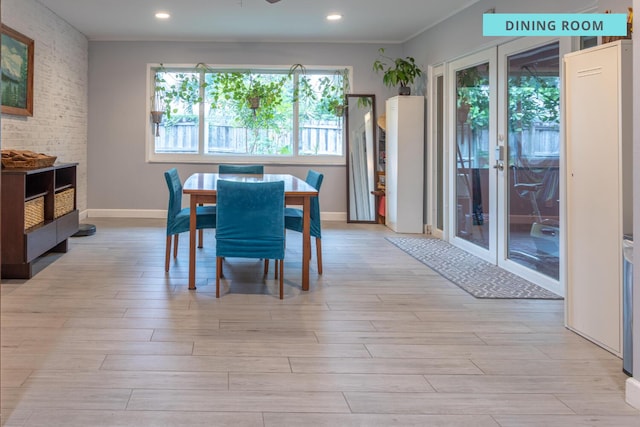 dining room with light hardwood / wood-style flooring, french doors, and brick wall