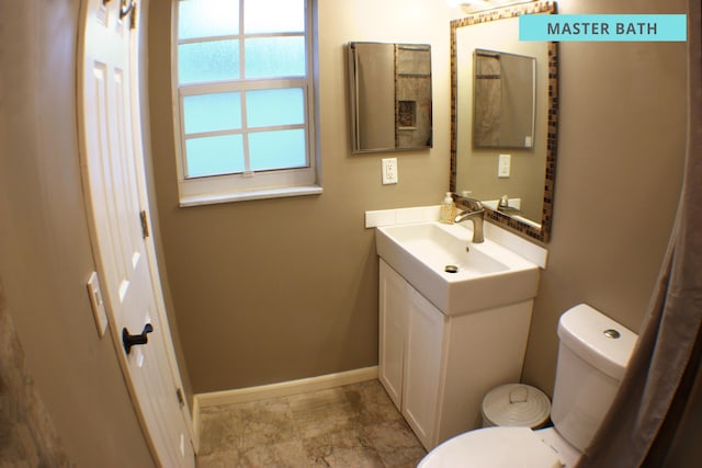 bathroom with toilet, vanity, and baseboards