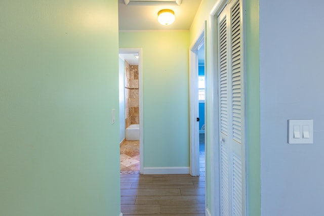 corridor featuring light wood-style flooring and baseboards