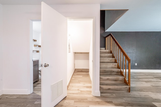 staircase featuring visible vents, baseboards, and wood finished floors