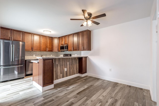 kitchen with stainless steel appliances, light wood finished floors, decorative backsplash, and a peninsula