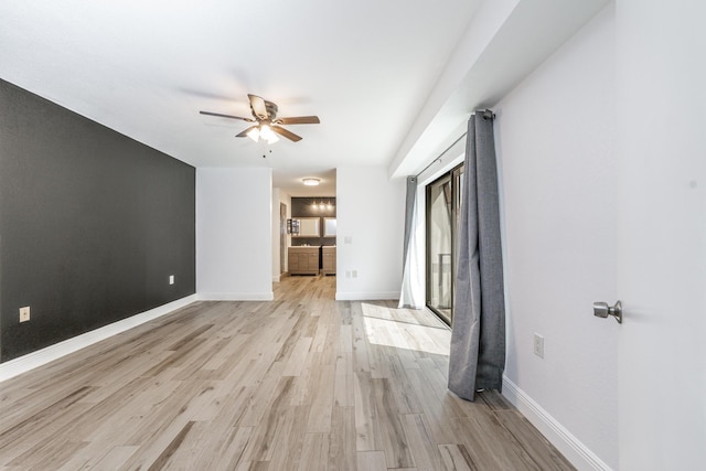 spare room with a ceiling fan, baseboards, and light wood finished floors