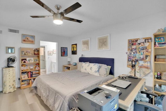 bedroom featuring ensuite bath, wood finished floors, visible vents, and a ceiling fan