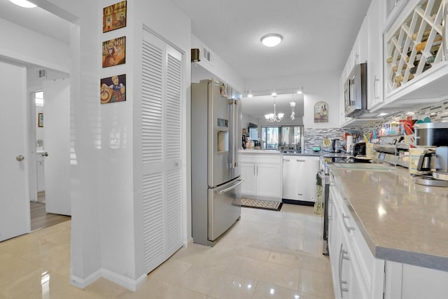 kitchen featuring light tile patterned floors, stainless steel appliances, white cabinets, tasteful backsplash, and pendant lighting