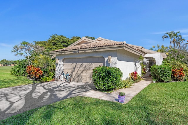 view of front of house with a garage, a front lawn, a tile roof, and stucco siding