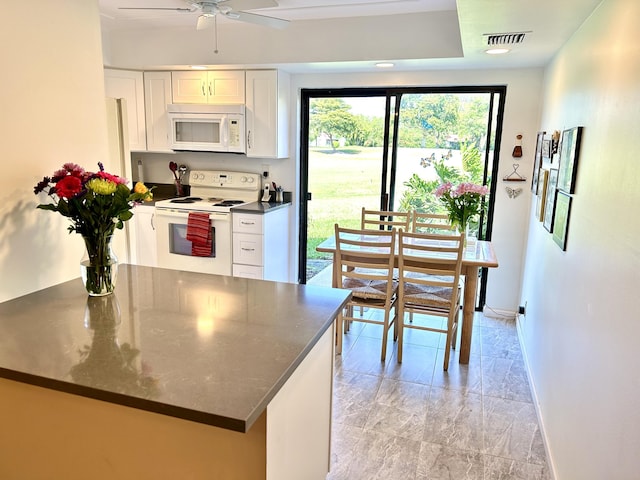 kitchen with white appliances, dark countertops, white cabinetry, and baseboards