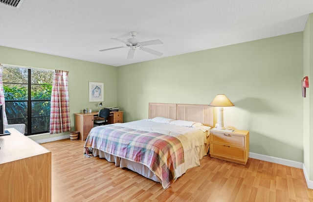 bedroom with visible vents, baseboards, a ceiling fan, light wood-style flooring, and a textured ceiling