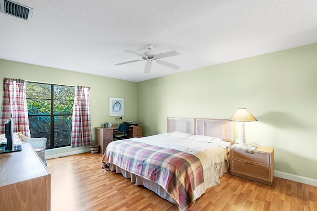 bedroom featuring a textured ceiling, light wood-style flooring, and visible vents