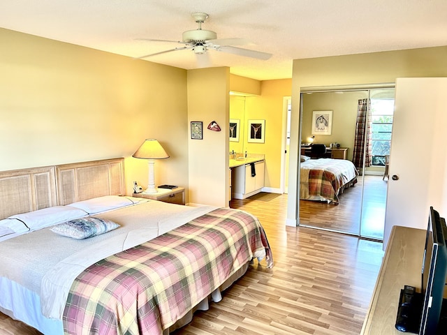 bedroom featuring ceiling fan, light wood-style flooring, a sink, baseboards, and a closet