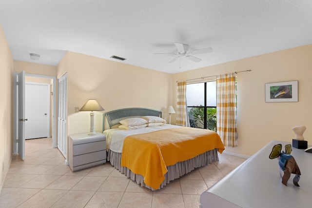 bedroom featuring light tile patterned floors, visible vents, ceiling fan, a textured ceiling, and baseboards