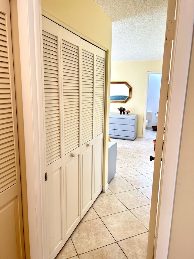 hall featuring light tile patterned floors and a textured ceiling