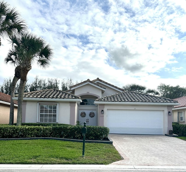 view of front facade with a tile roof, an attached garage, decorative driveway, a front yard, and stucco siding