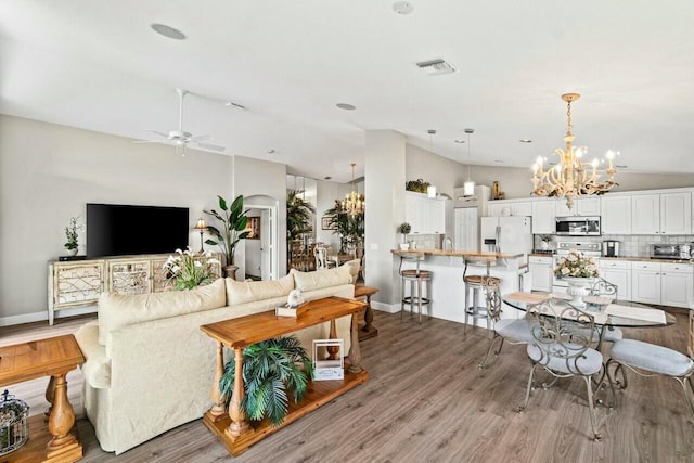 living room featuring wood finished floors, a toaster, ceiling fan with notable chandelier, baseboards, and visible vents