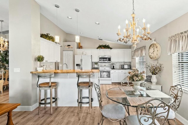 dining room with vaulted ceiling, a notable chandelier, and light wood-style flooring