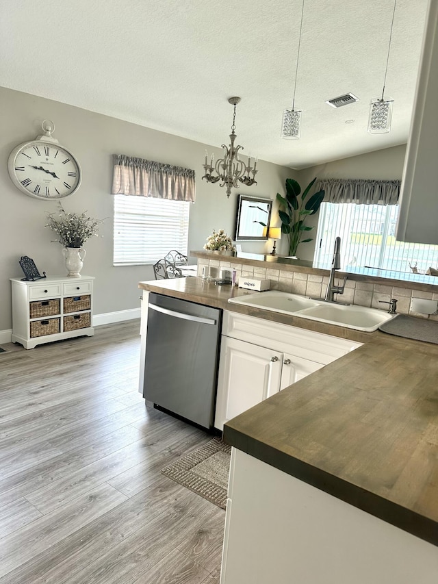 kitchen featuring dark countertops, visible vents, white cabinetry, a sink, and dishwasher