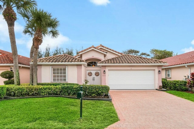 mediterranean / spanish home with a tile roof, an attached garage, decorative driveway, a front lawn, and stucco siding