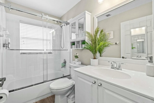 bathroom with vanity, toilet, combined bath / shower with glass door, visible vents, and wood finished floors