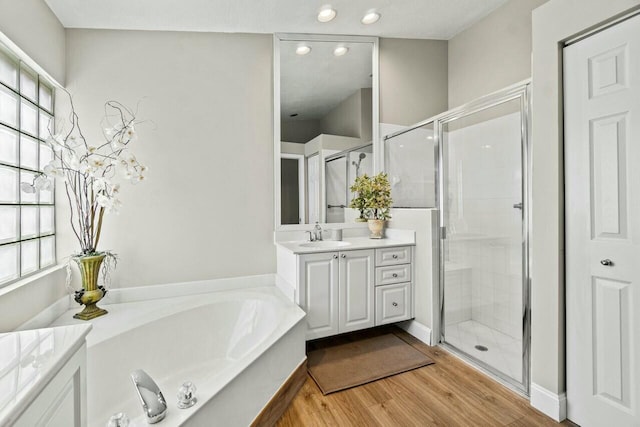 bathroom featuring recessed lighting, vanity, a stall shower, a garden tub, and wood finished floors