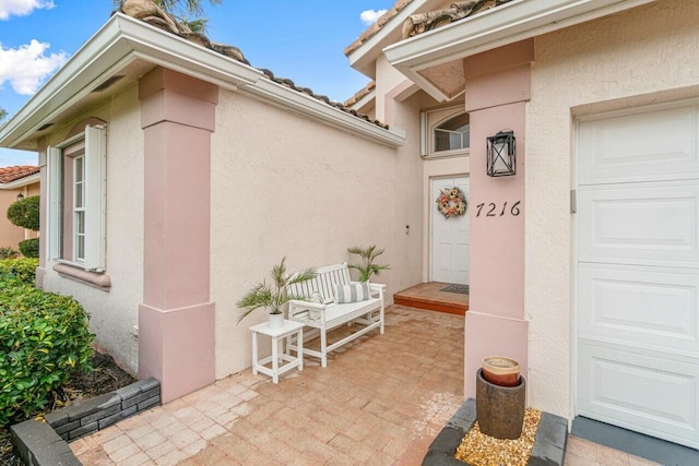 view of exterior entry featuring an attached garage and stucco siding