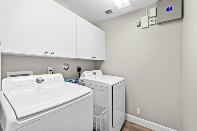 laundry area featuring cabinet space, visible vents, baseboards, washer and dryer, and wood finished floors