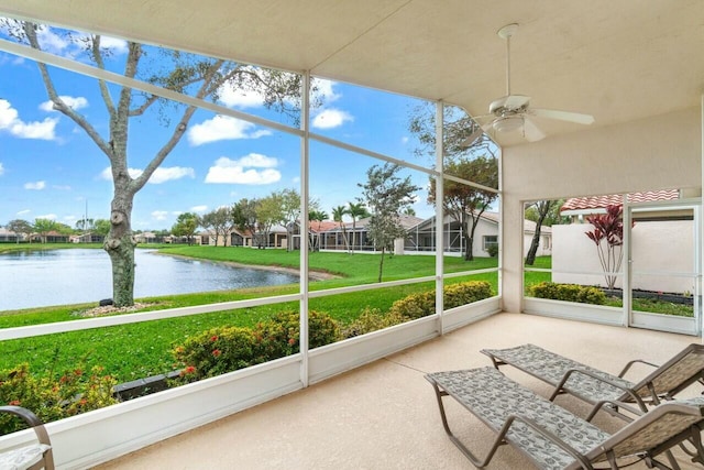 unfurnished sunroom with ceiling fan, a water view, and a residential view